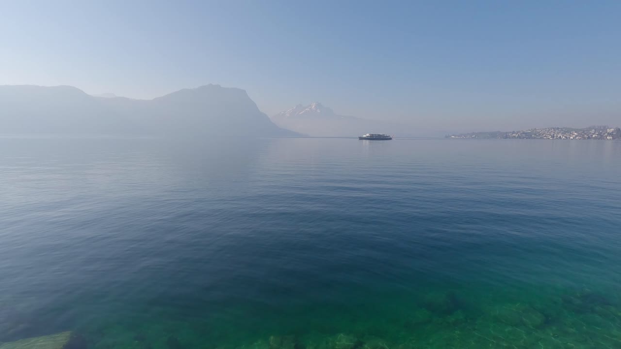 Misty morning on lake Lucerne in Switzerland with boat passing by the mountain view