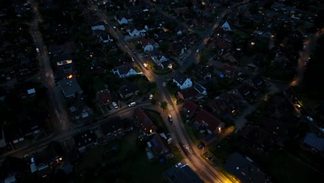 quiet neighborhood with warm lighting lantern along street with parking cars. single family houses and homes along road in america. night scene with cozy atmosphere. aerial top down shot in u.s