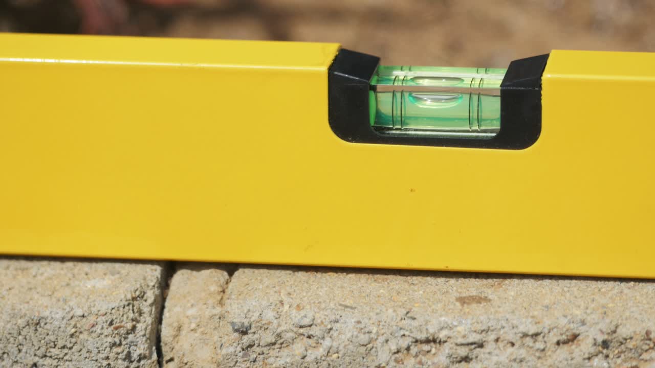 el nivel de los constructores se coloca en una pared de ladrillos durante la construcción de cerca