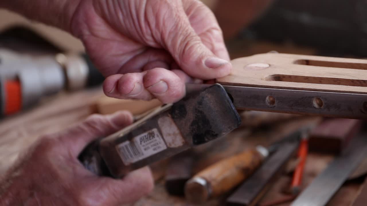 Artisan from Madeira builds headstock of guitar. Close up handheld