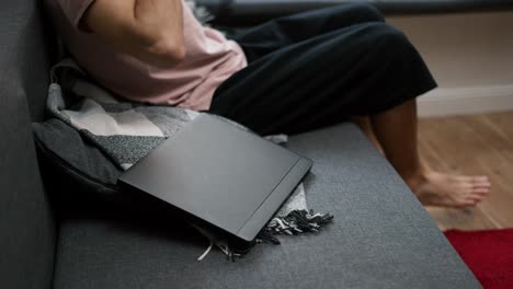 Cropped-view-of-a-man-putting-on-headphones-scrolling-social-media-on-laptop-at-home