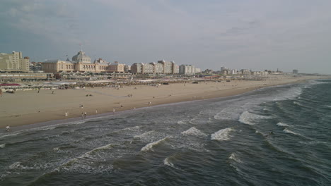 aerial drone wide and high angle landscape footage of european beach resort in the netherlands, the hague city town with sea water waves and seashore view