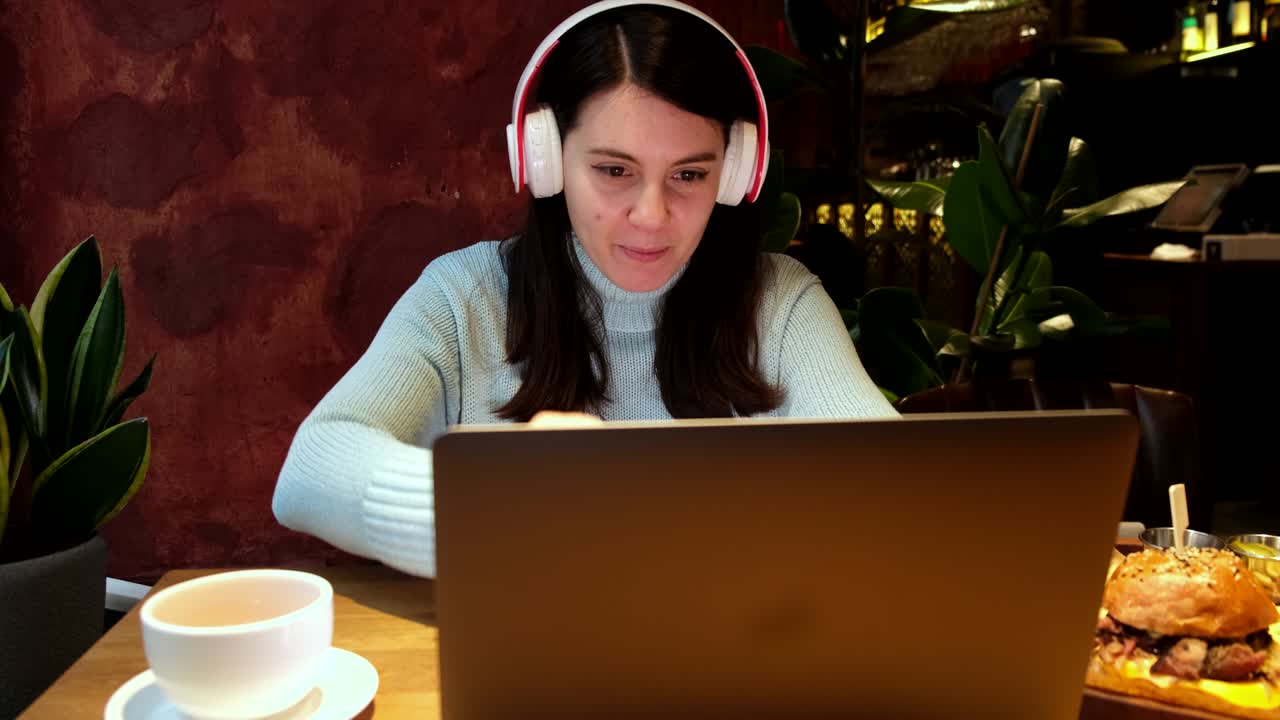 woman freelancer working in cafe listening music in headset