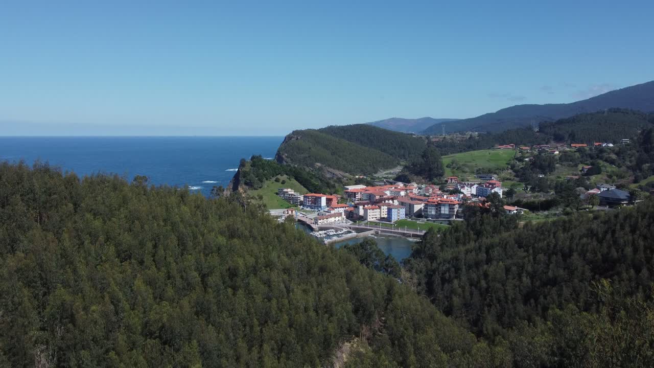 Villaggio di pescatori basco rivelato mentre la ripresa aerea si innalza dagli alberi della foresta