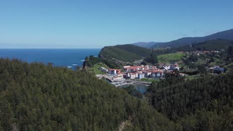 basque fishing village revealed as aerial rises out of forest trees