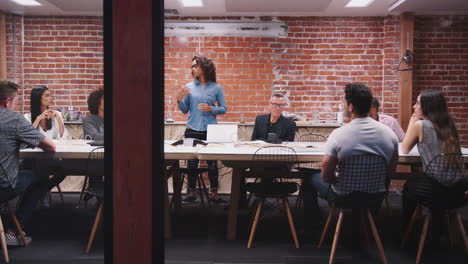 Equipo-De-Negocios-Teniendo-Una-Reunión-Nocturna-Sentados-Alrededor-De-La-Mesa-De-La-Sala-De-Juntas