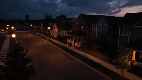 Aerial-flight-over-empty-street-in-american-neighborhood-and-orange-colored-streetlamps-at-night