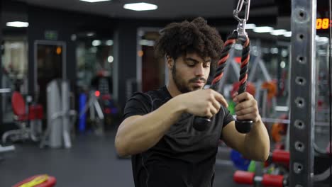 young man exercising on multi station at gym, close up