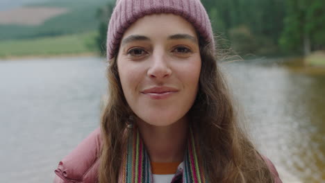 portrait happy woman smiling feeling joy wearing beanie enjoying cold winter outdoors in nature by lake real people 4k