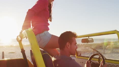 Happy-caucasian-couple-sitting-in-beach-buggy-by-the-sea-talking