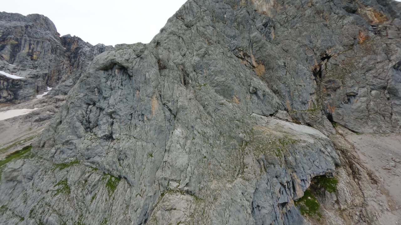 el vuelo del avión no tripulado de fpv se acerca a una empinada pared de montaña gris de dachstein en austria