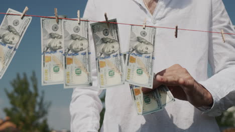 a man removes banknotes from a clothesline. money laundering concept