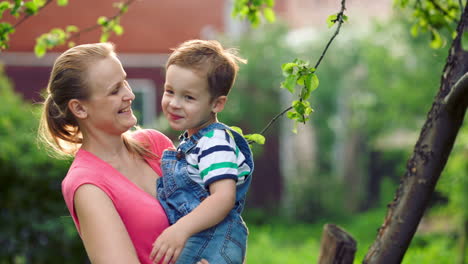 Madre-Sosteniendo-A-Su-Hijo-Y-Hablando-Al-Aire-Libre