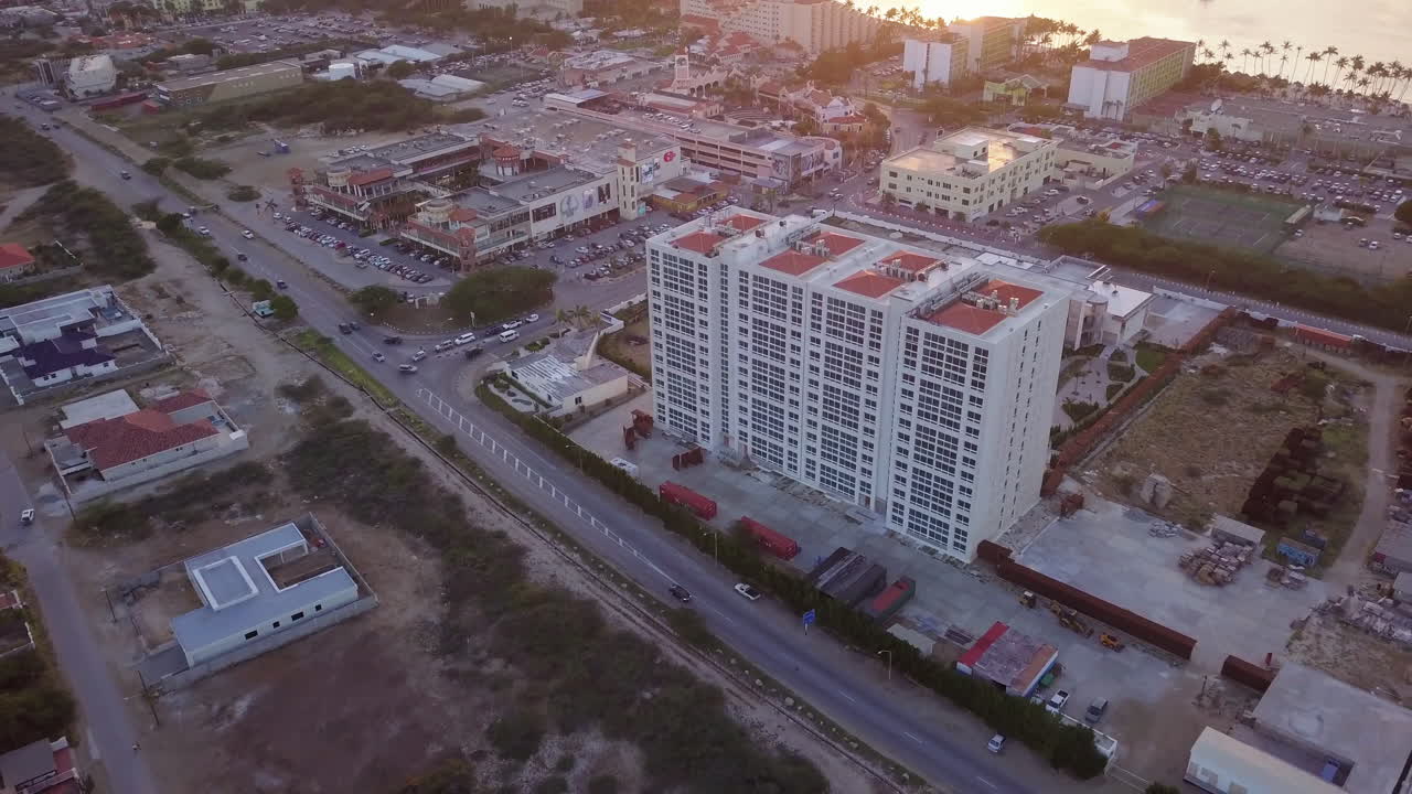 los coches pasan por un gran hotel a lo largo de la autopista de palm beach, aruba