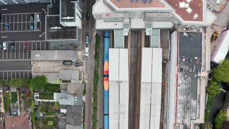 Top-down-Drone-shot-over-South-Western-British-Rail-train-leaving-Twickenham-station