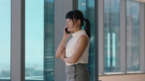 asian business woman using smartphone corporate sales executive chatting to client financial advisor negotiating deal sharing expert advice having phone call in office looking out window