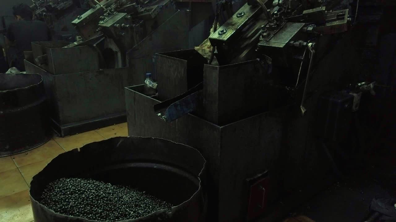 el primer plano de los tornillos cae en el contenedor de la máquina para fabricar tornillos