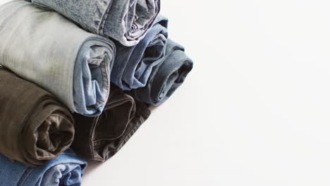 Close-up-of-folded-jeans-with-different-shades-on-white-background-with-copy-space