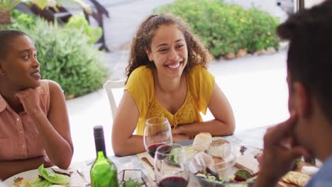 feliz mujer biracial riendo con amigos en la fiesta de la cena en el patio