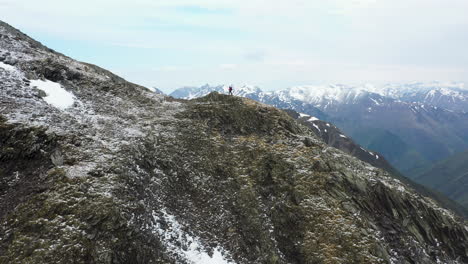 Revealing-drone-shot-of-hiker-standing-on-top-of-a-mountain-ridge-in-the-snow-covered-Caucasus-Mountains-in-Georgia