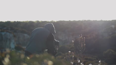 photographer looks through camera on tripod while sunset to make a picture of the stunning landscape in mallorca, spain - slow motion