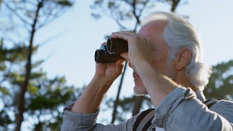 senior man looking through binoculars at countryside 4k