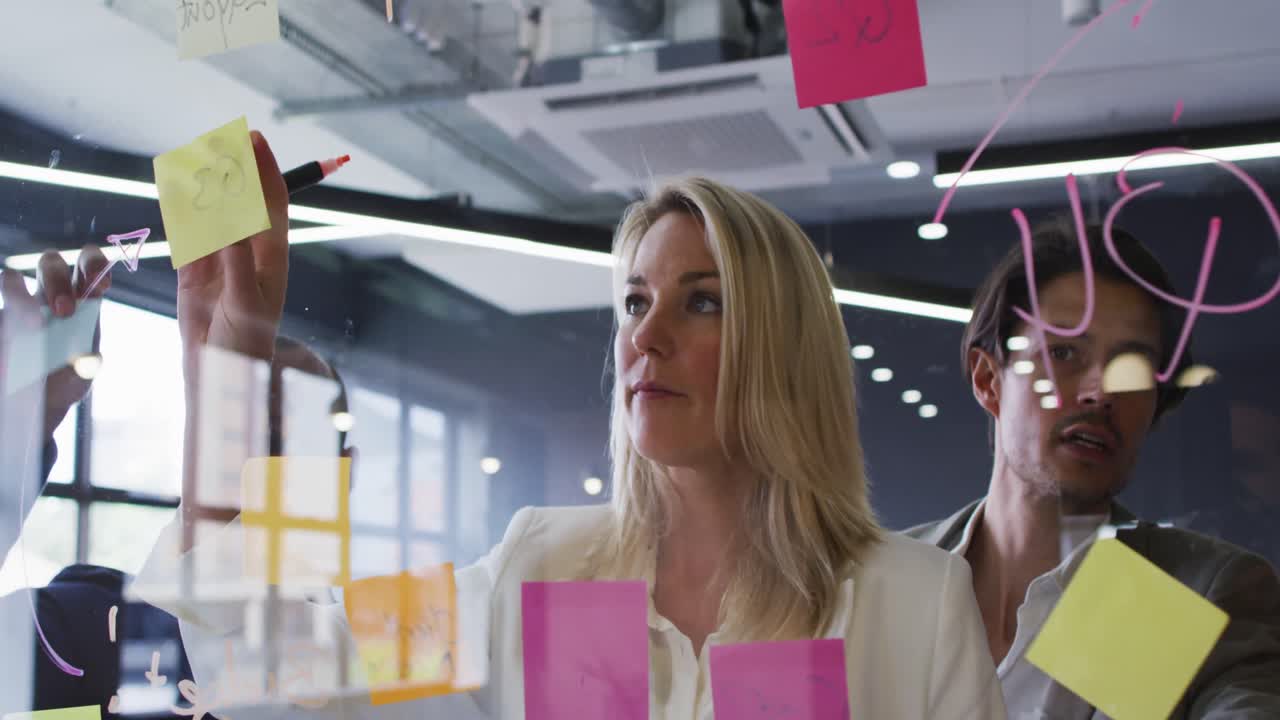 Diverse business people standing using a board brainstorming in modern office
