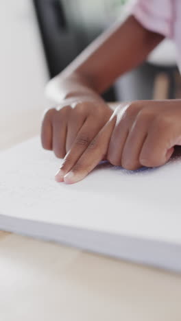 vertical video of biracial girl reading braille, slow motion