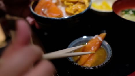 comiendo sashimi don con palillos