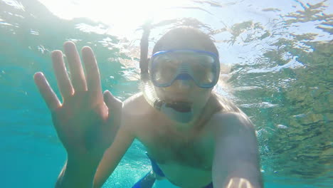 diver makes selfie waving at the camera - underwater