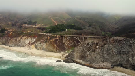 vuelo aéreo de drones sobre una pequeña playa y un mar esmeralda en la costa de big sur, oeste de california, con poderosas olas rompiendo