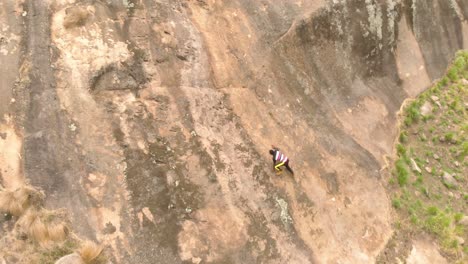 a birds eye view shot of an african man rock climbing up a granite rock in africa