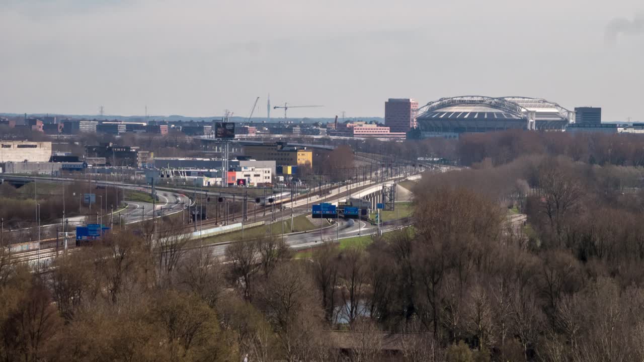 Timelapse video of traffic on the highway and trains passing by along the south side of Amsterdam. The soccer stadium 'Arena' can be seen in the distance.