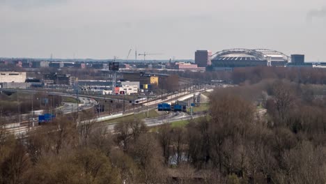 timelapse video of traffic on the highway and trains passing by along the south side of amsterdam. the soccer stadium 'arena' can be seen in the distance.