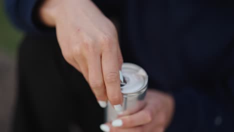 woman hold and use fingers to open sealed carbonated aluminium beverage can