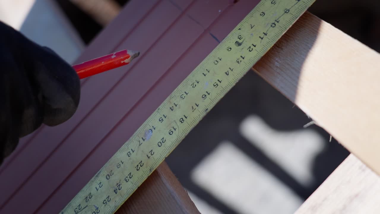 Worker using a ruler and pencil to mark measurements on building materials