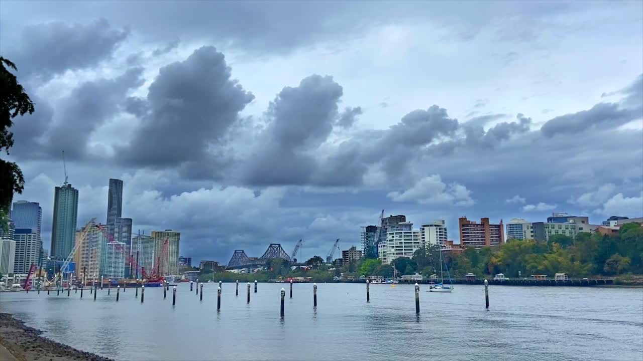 브리즈번 강 정박지에서 호주 브리즈번 시내의 스토리 브리지를 향해 매우 극적이고 영화적인 전망을 감상할 수 있으며 위협적인 폭풍우 구름이 머리 위로 쌓입니다.