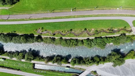 aerial top down shot of clear river in swiss valley during sunny day. street and path in suburb of switzerland in fall.