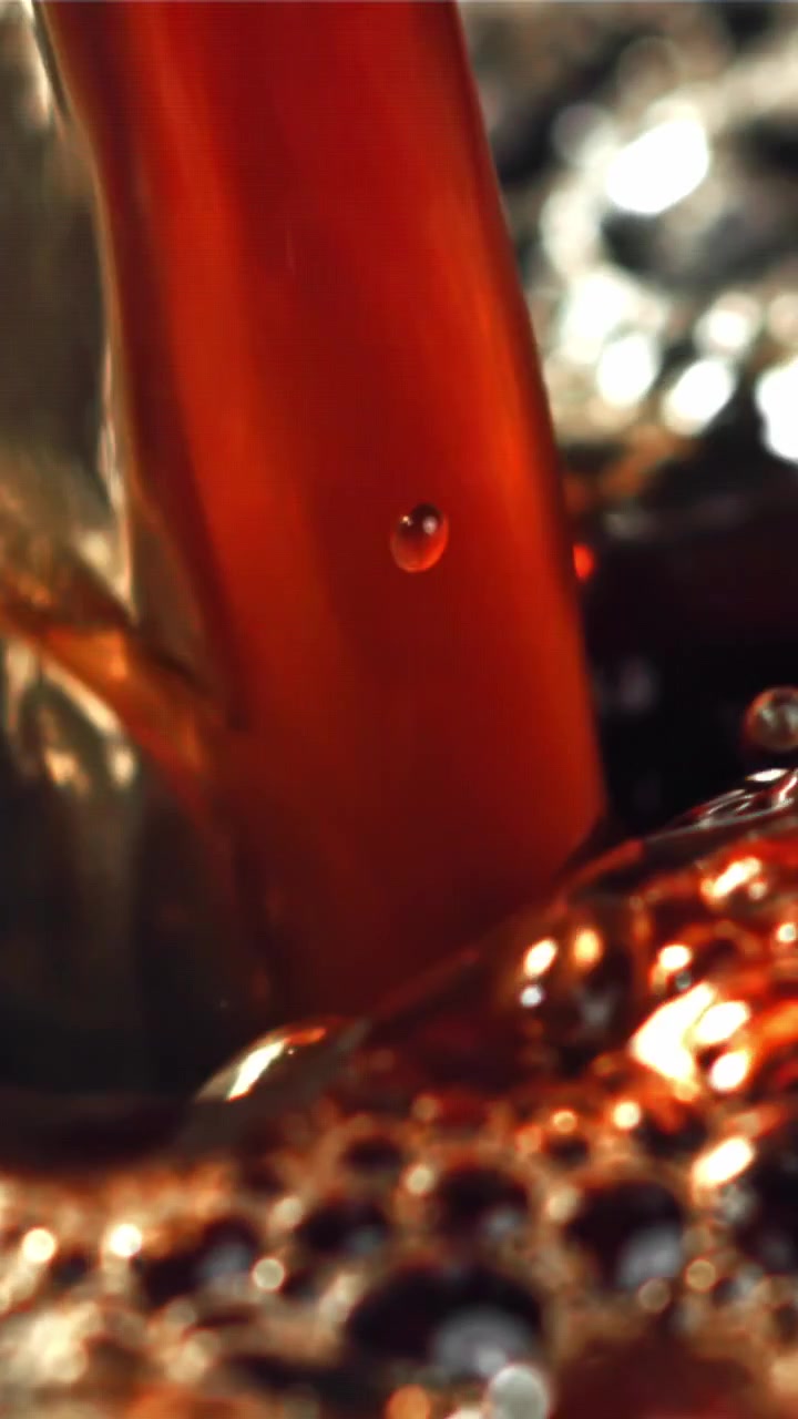 Versamento al rallentatore di liquido scuro con bolle e bokeh