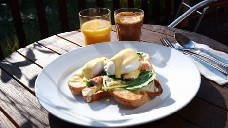 Rich-breakfast-of-Eggs-Benedict-poached-eggs,-spinach,-bacon-and-hollandaise-on-toasted-bread