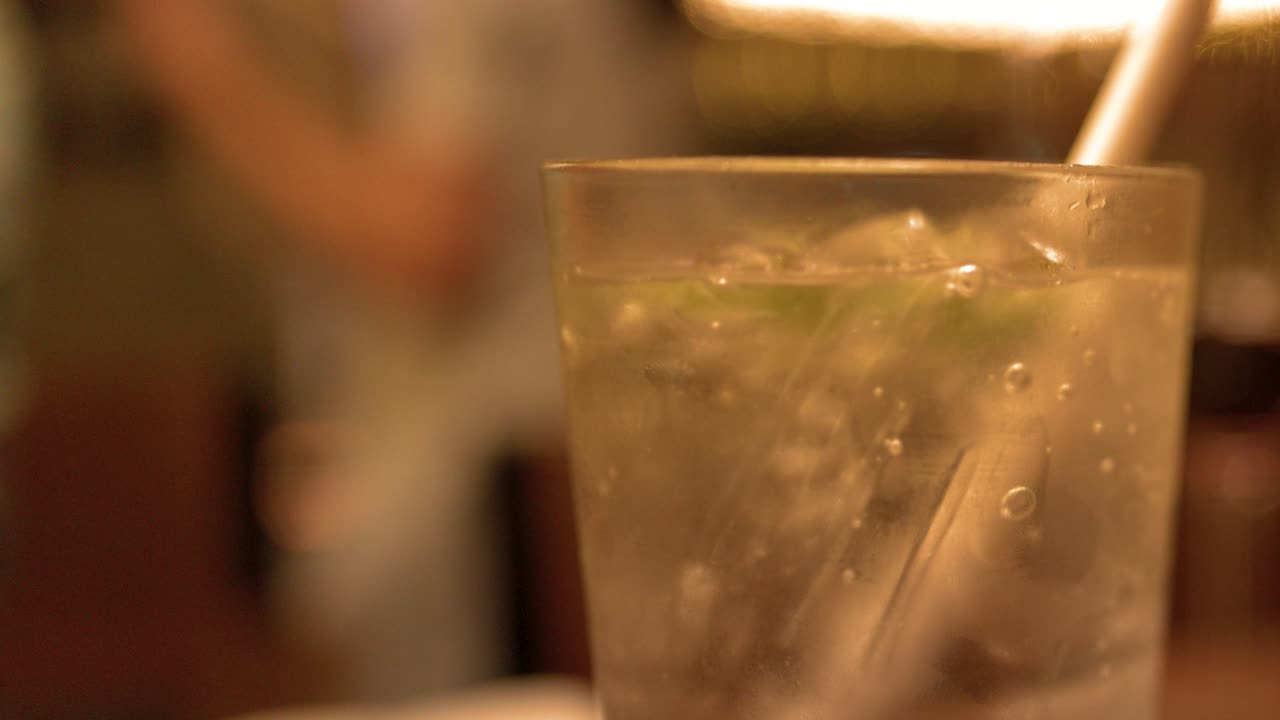 賑やかなレストランで、氷の入った冷たい炭酸飲料をクローズアップで撮影。