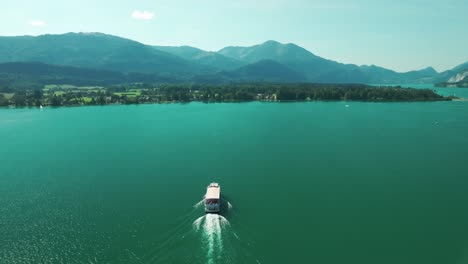 drone follows a boat gliding across the turquoise waters of wolfgangsee lake