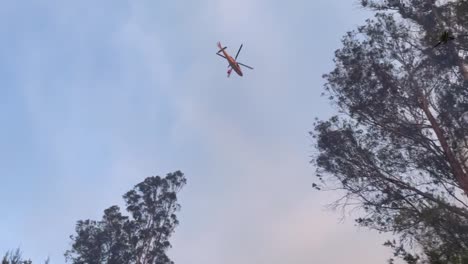 Ein-Amphibienhubschrauber,-Der-Wasser-Auf-Seinem-Monsuneimer-Transportiert,-Eilt-Herbei,-Um-Wasser-Auf-Ein-Verheerendes-Feuer-Zu-Werfen,-Das-Das-Gebiet-Verwüstet