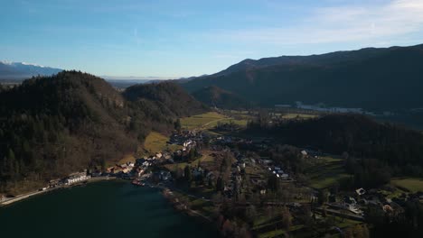 cinematic aerial view above houses in village next to lake bled