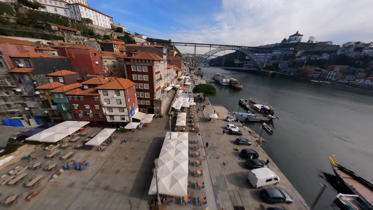 Casas e edifícios ribeirinhos sobrevoando rapidamente com drone FPV na Ponte Dom Luís, Porto, Portugal.