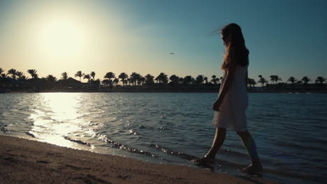 Hermosa-Mujer-Caminando-Por-La-Bahía-Del-Mar-Al-Atardecer.-Niña-Disfrutando-Del-Tiempo-De-Vacaciones