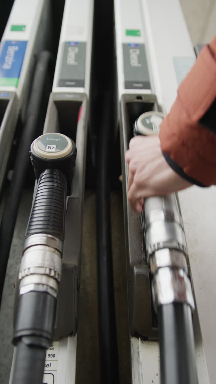 Gas pump with hand taking one during the high fuel prices