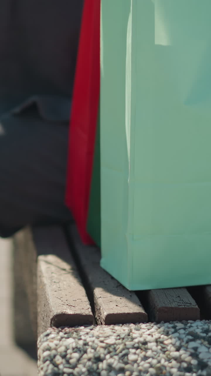 벤치에 쇼핑백을 놓고 앉아서 오른쪽 다리를 왼쪽 다리에 는 개인의 클로즈업 다리 시각, 자전거를 타는 사람을 특징으로하는 흐릿한 배경