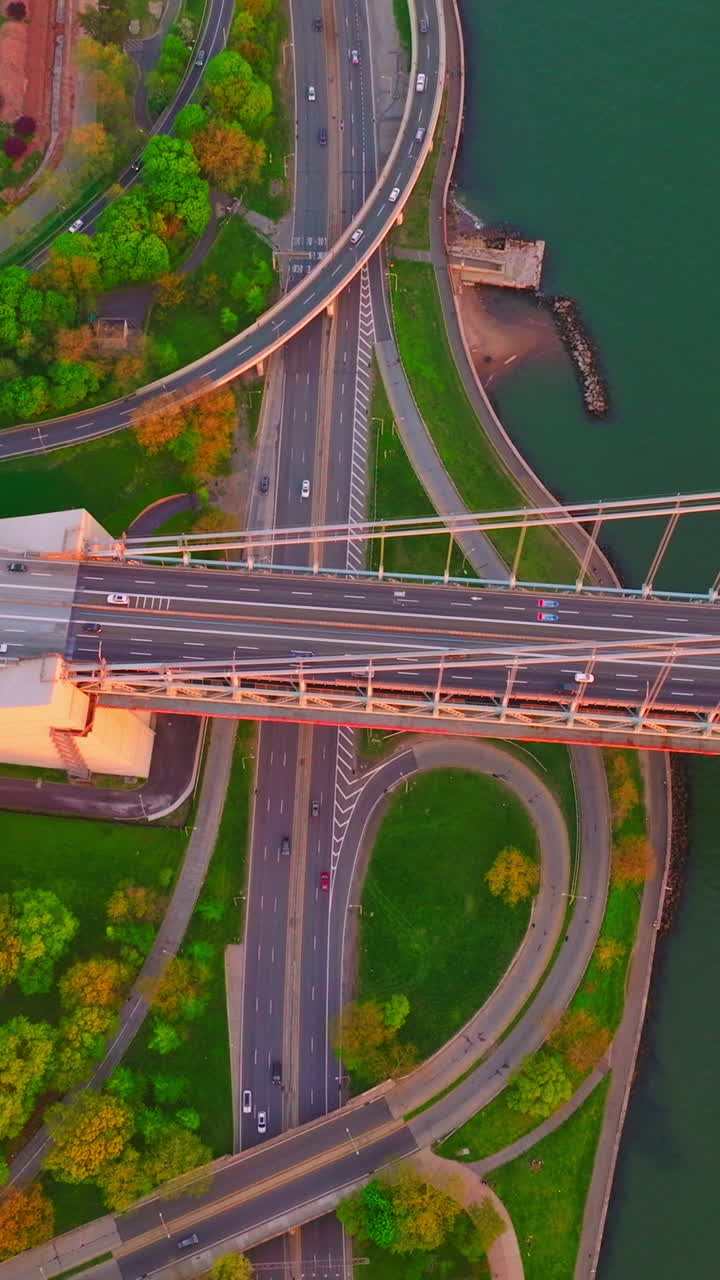 Lively motorways at the bank of the East River. Top view on the bridge, roads, green waterfront and sea-green water. Vertical video