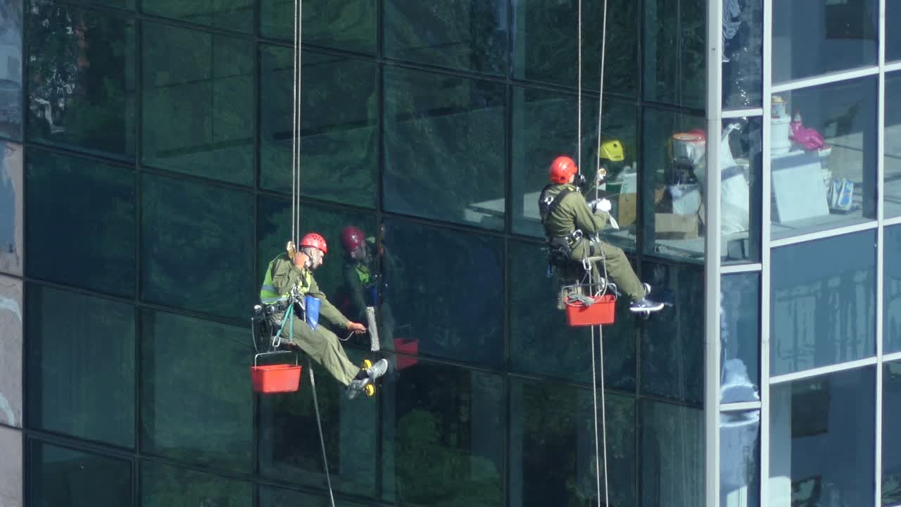 trabaja en alta altitud. un trabajador lava las ventanas de un rascacielos. el escalador lava ventanas en altura. un esturión lava ventanas de un rascacielo.